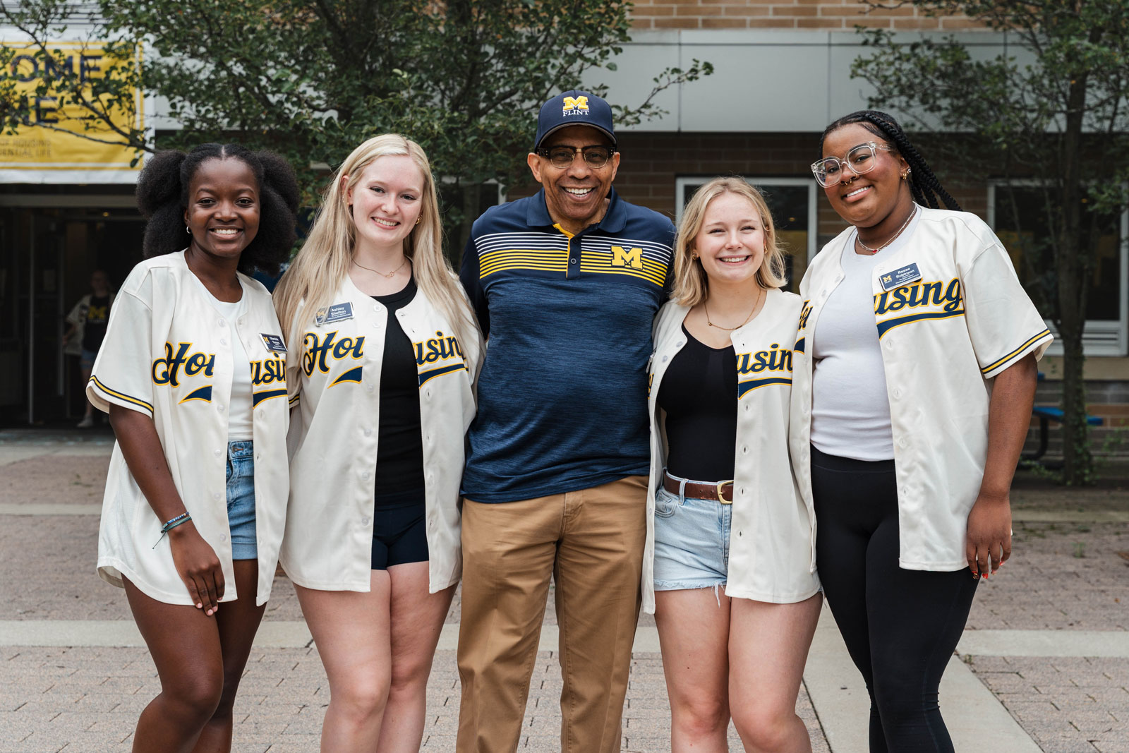 UM-Flint Chancellor Laurence B. Alexander posing with group of students on campus.